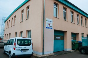 Gebäude der Firma Actemium am Standort Bitterfeld. Vor dem Gebäude steht ein weißer Ford mit Actemium Logo.