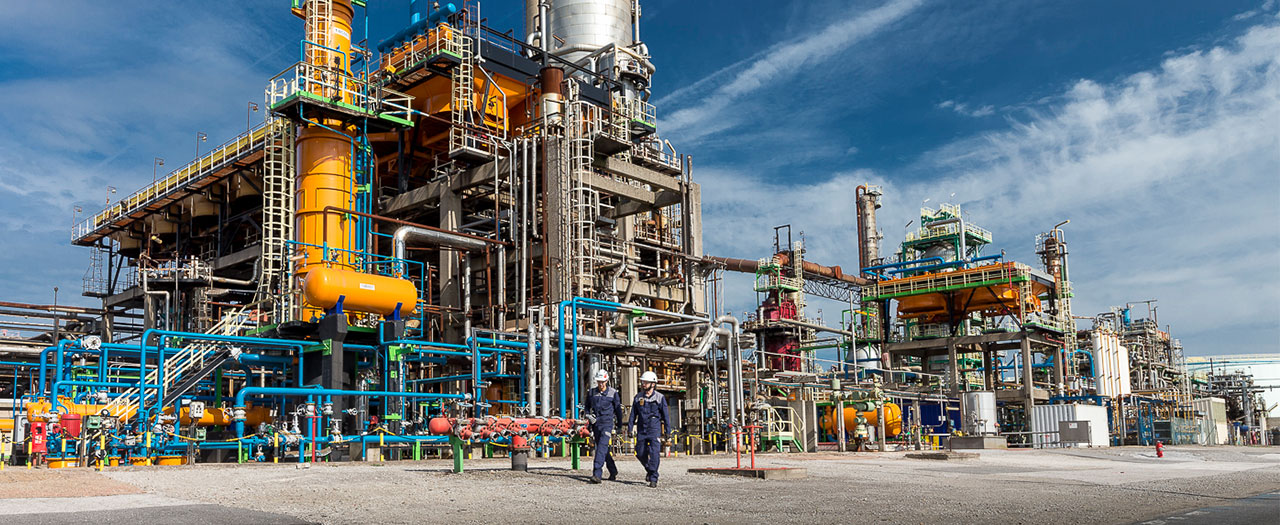 Männer vor einer großen industriellen Anlage