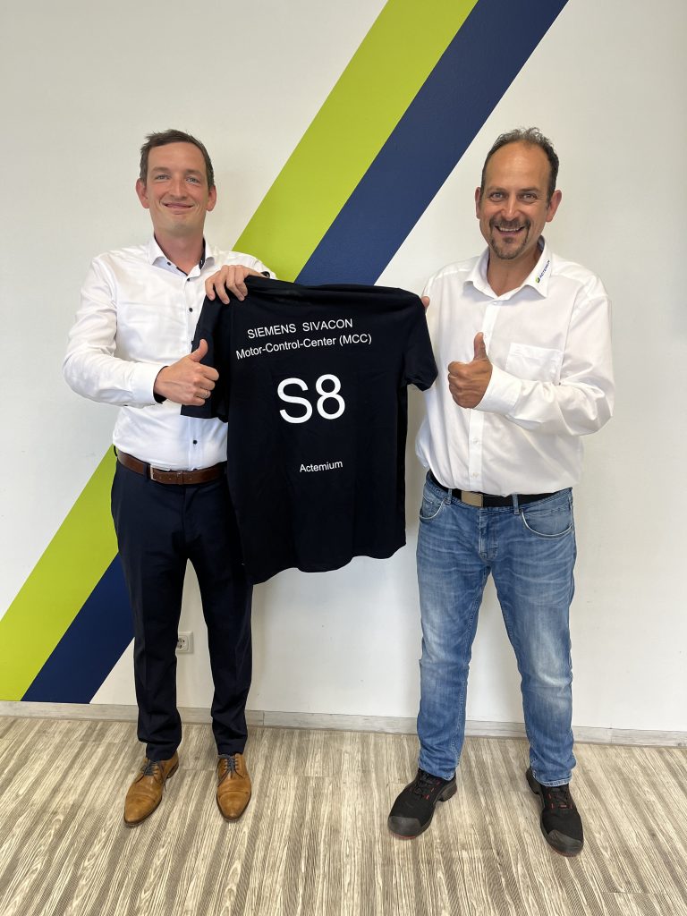 zwei Männer stehen nebeneinander vor einem Schaltschrank